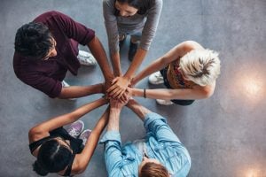 Photo of a team of people putting their hands together in a circle