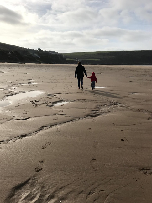 Photo of father and son walking along the beach holding hands