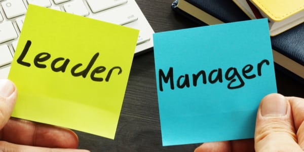 Photo of two post-it notes one saying leader the other manager