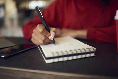 Close up of person writing in a notebook