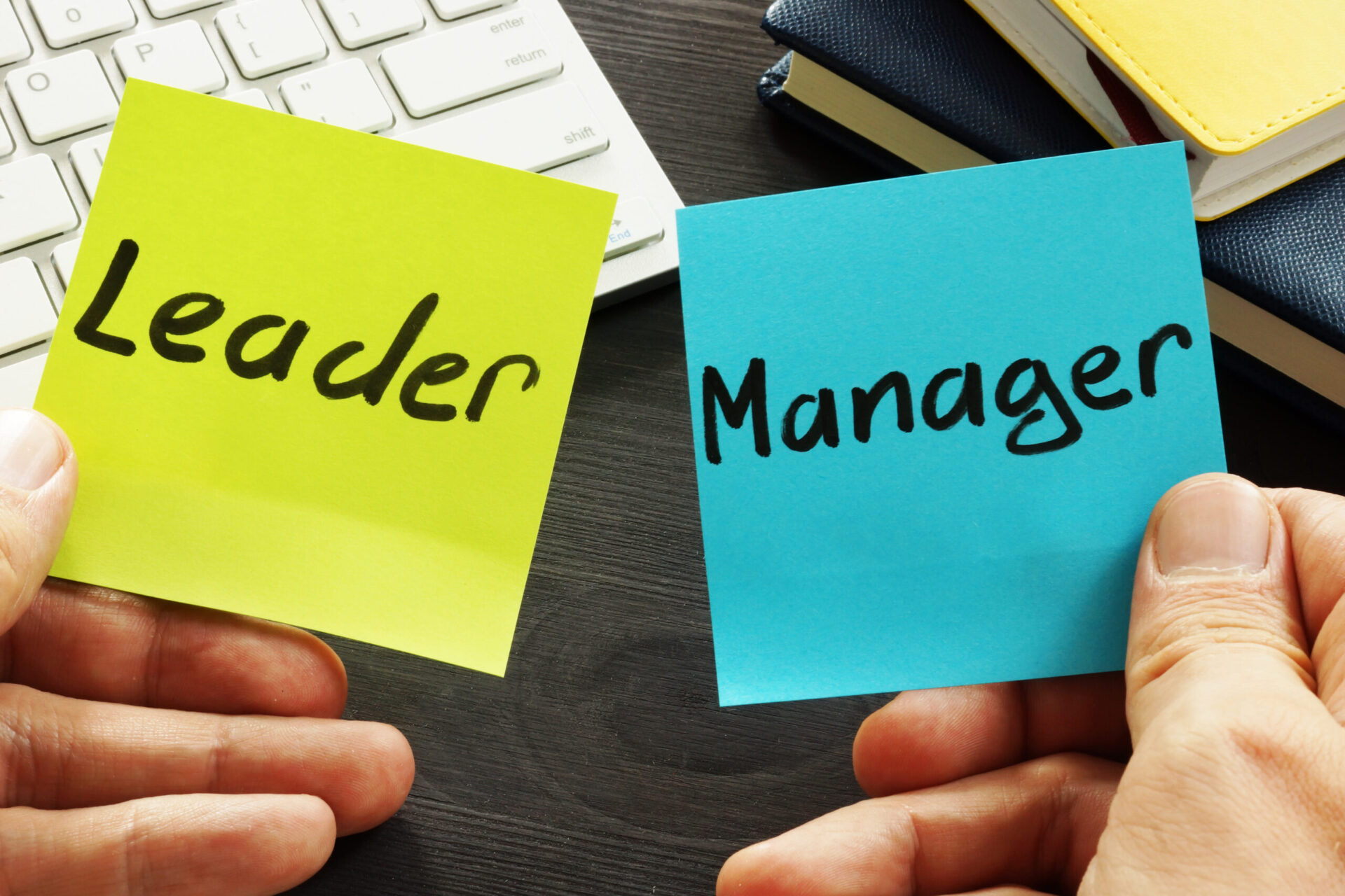 Photo of a post-it-note that says 'leader' and another that says 'manager'