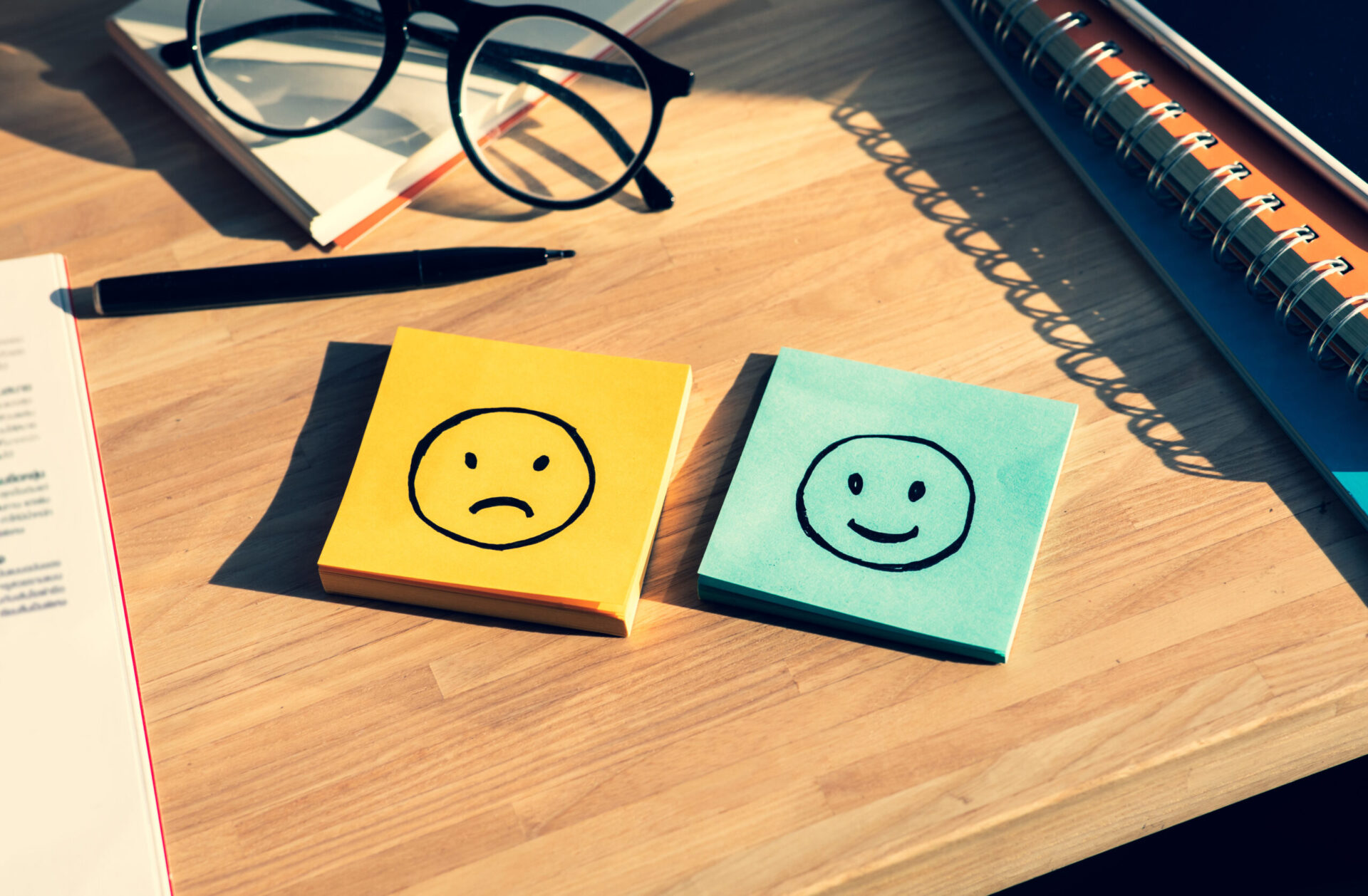 Photo of a post-it-note with a sad face and one with a happy face