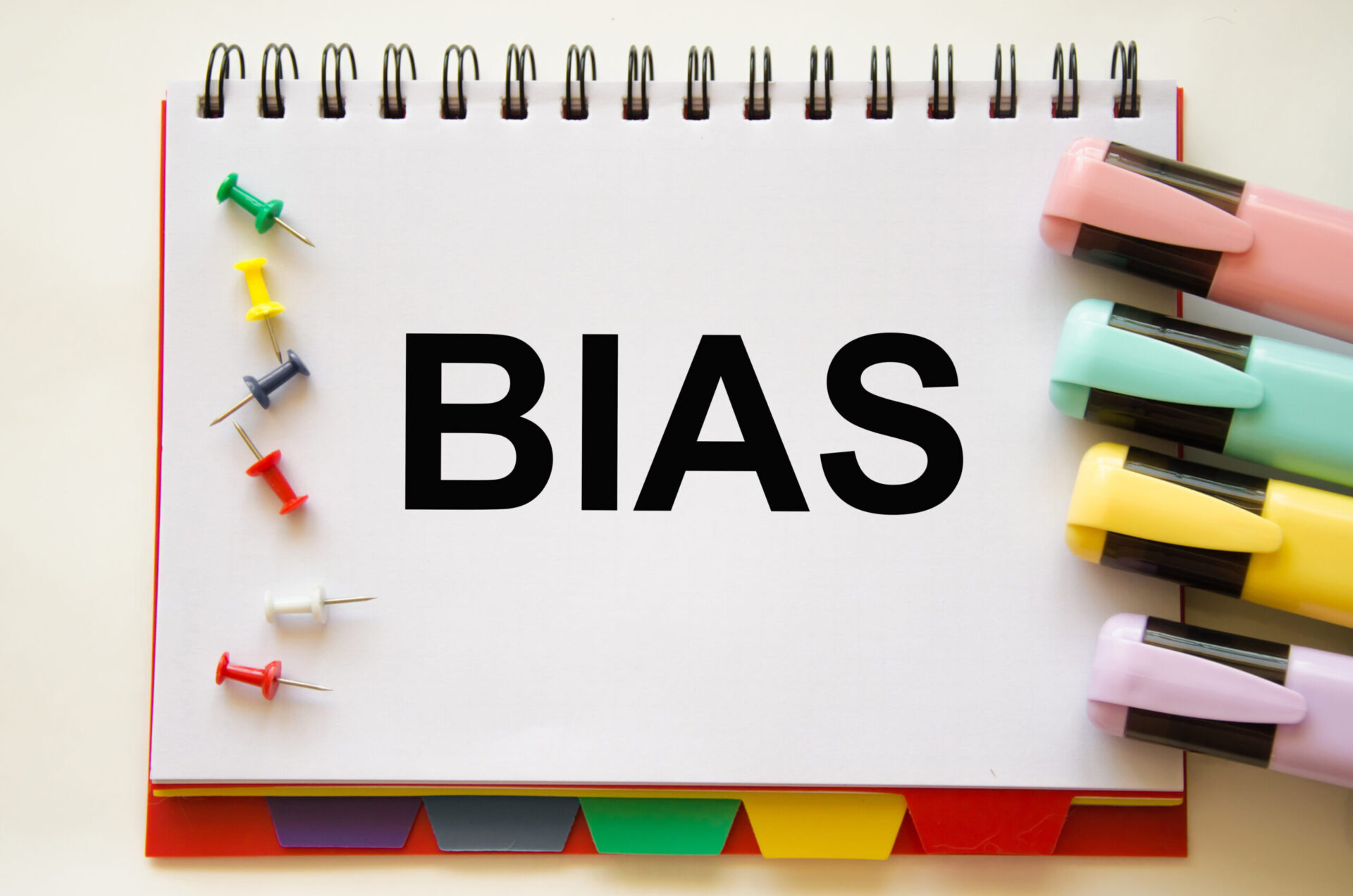 Photo of the word 'BIAS' on a notepad next to some pins and highlighters