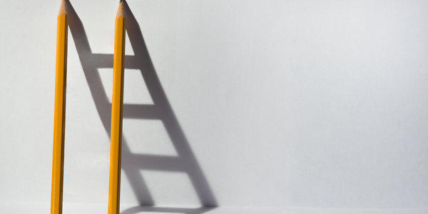 Photo of two pencils leaning against a wall creating a ladder shaped shadow