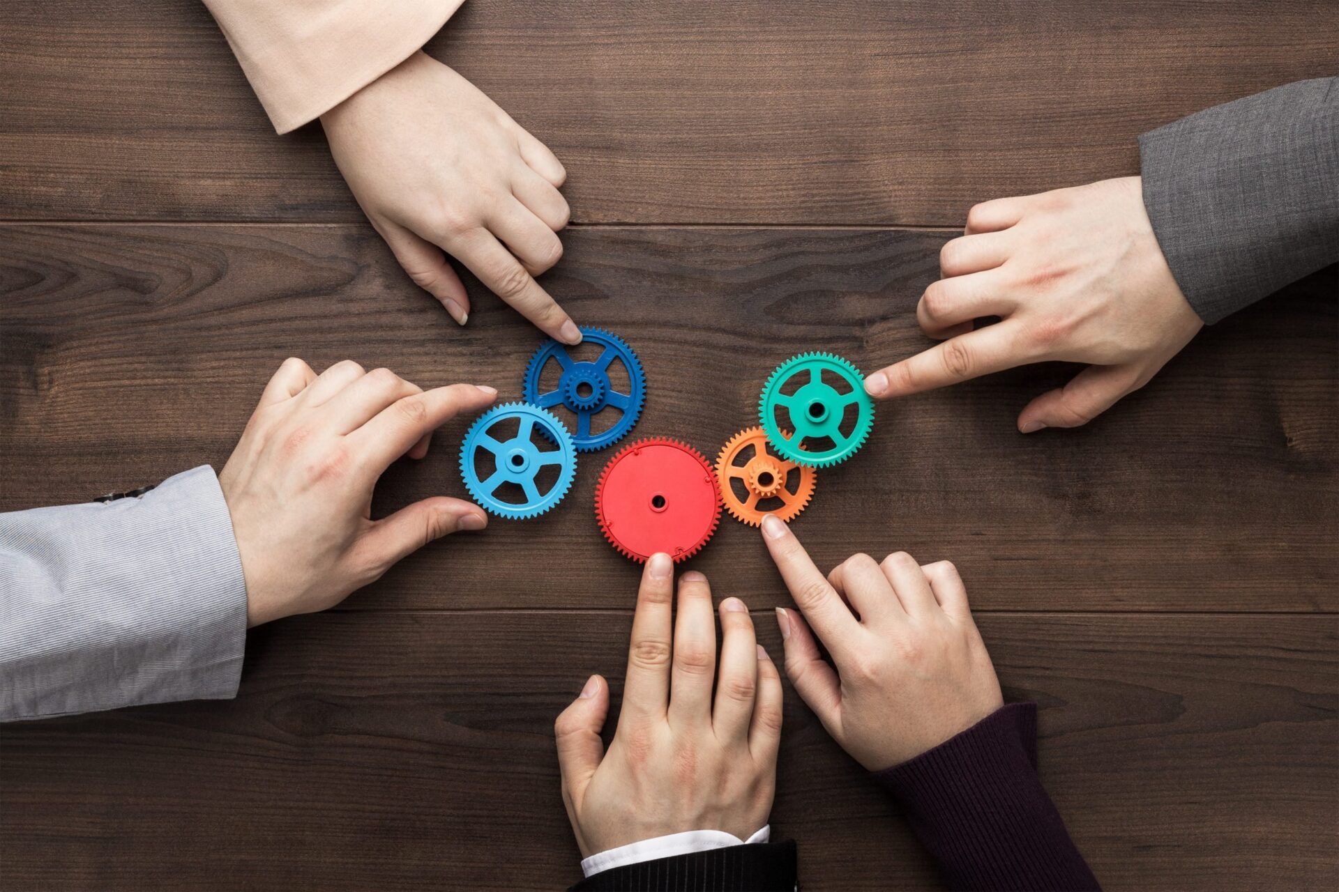 Photo of people each placing a different coloured cog on a table