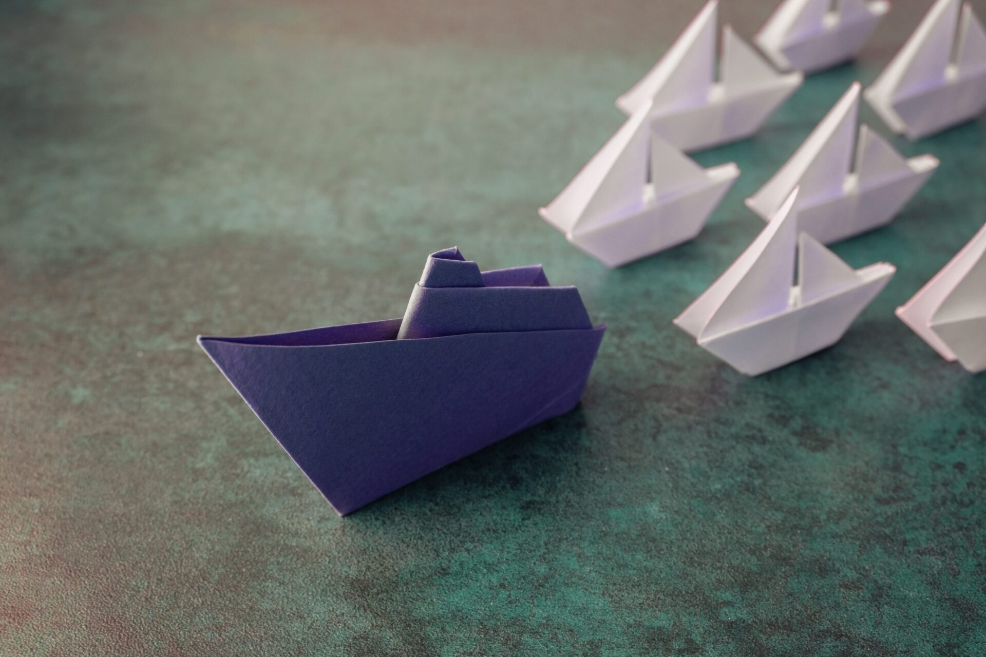 Photo of a blue paper boat leading other white ones