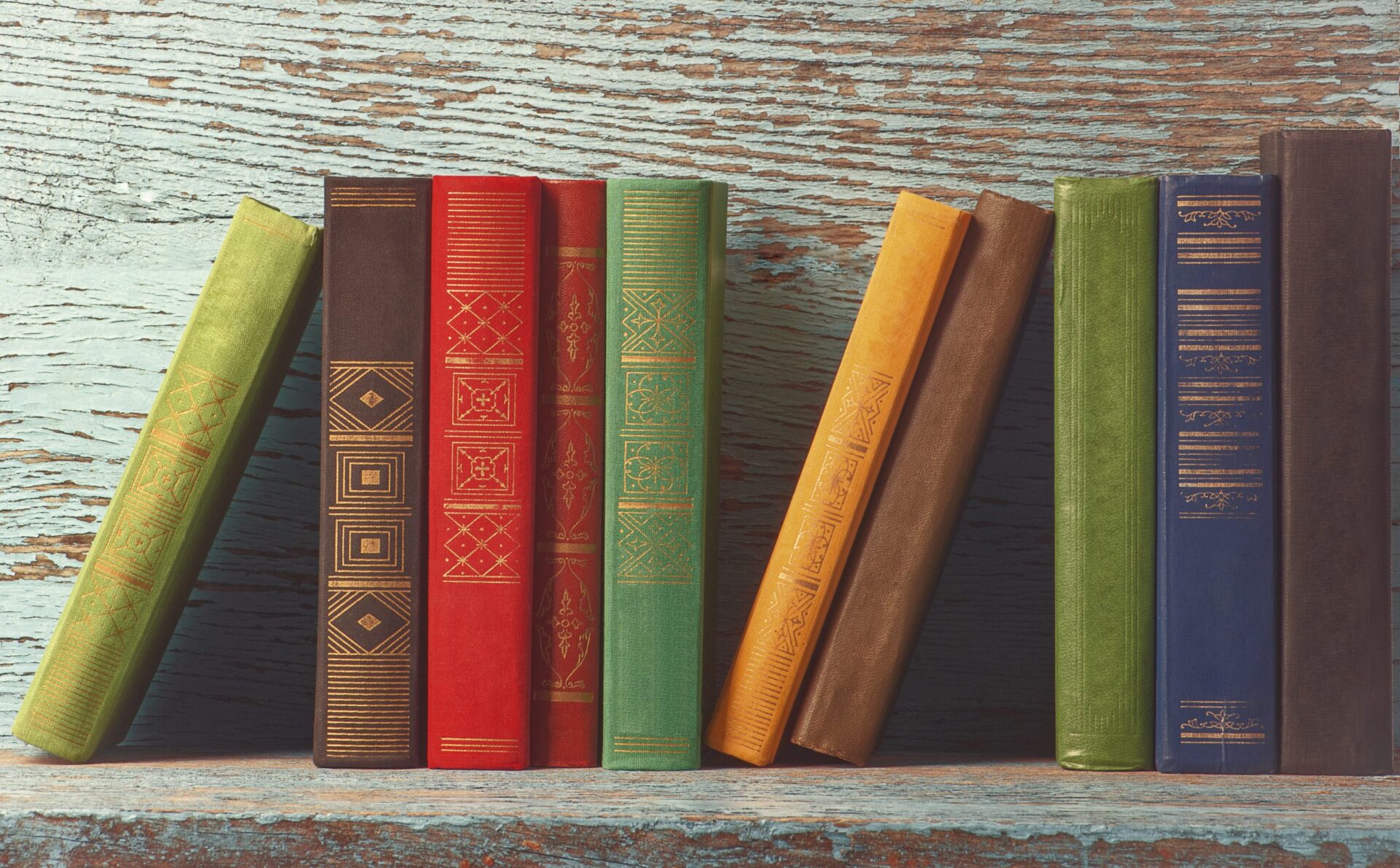 Photo of books stacked along side each other on a shelf