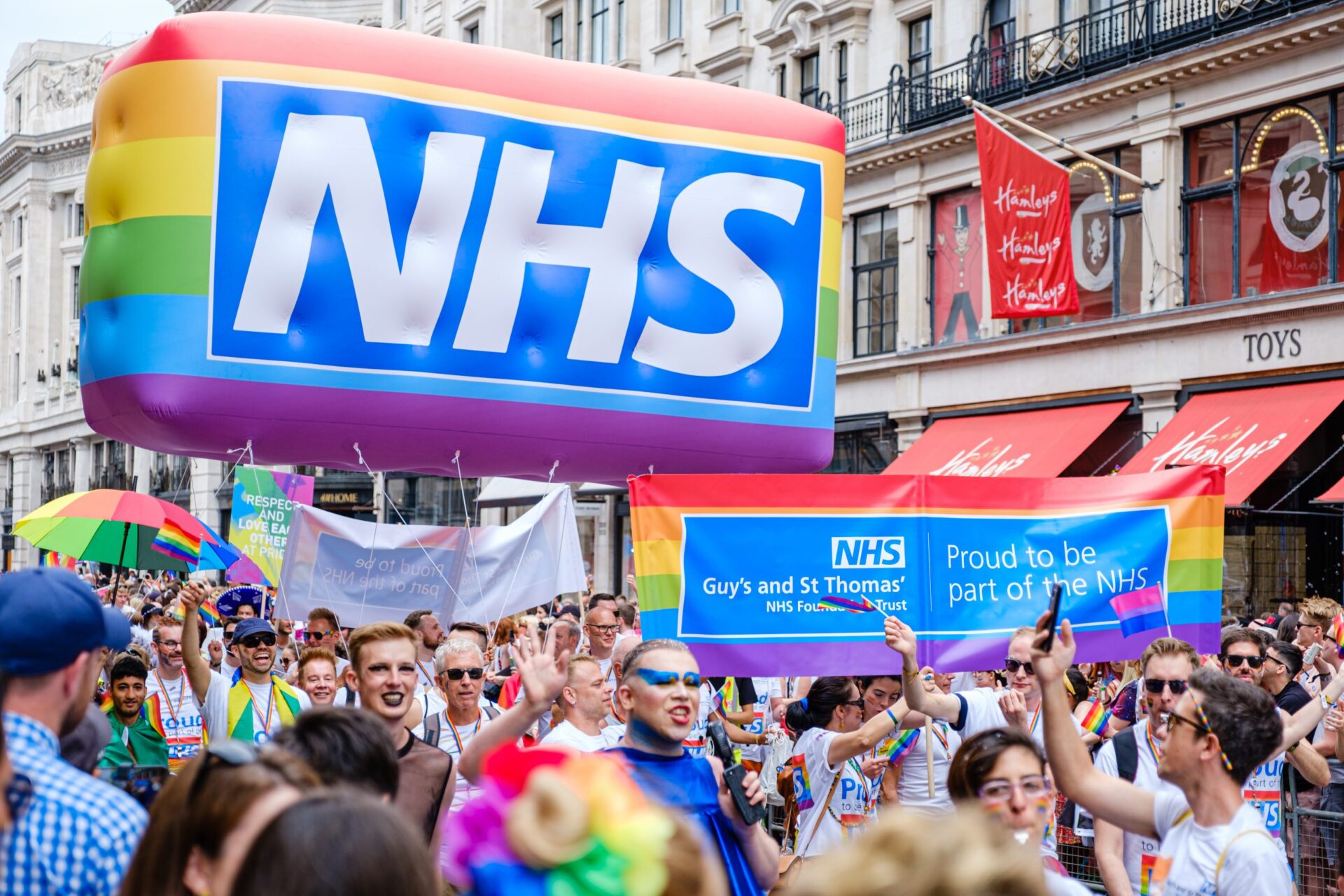 Photo of a multi-coloured balloon with the NHS logo on it, in a large crowd of people